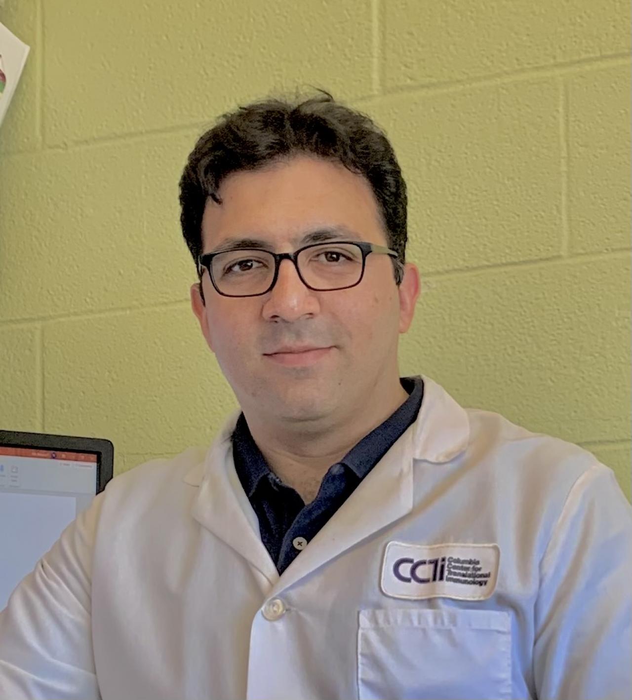 Mohsen Maharlooei, PhD, in a lab setting wearing a white coat