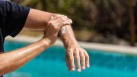 Man applies sunscreen to his arm