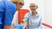 A healthcare professional drawing blood from the arm of an older person.