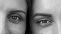 Two women with their heads side by side. The image is black and white with only one eye showing for each woman.