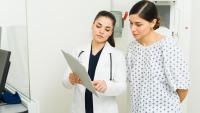 A healthcare professional speaking with a patient while they both look at a clipboard.